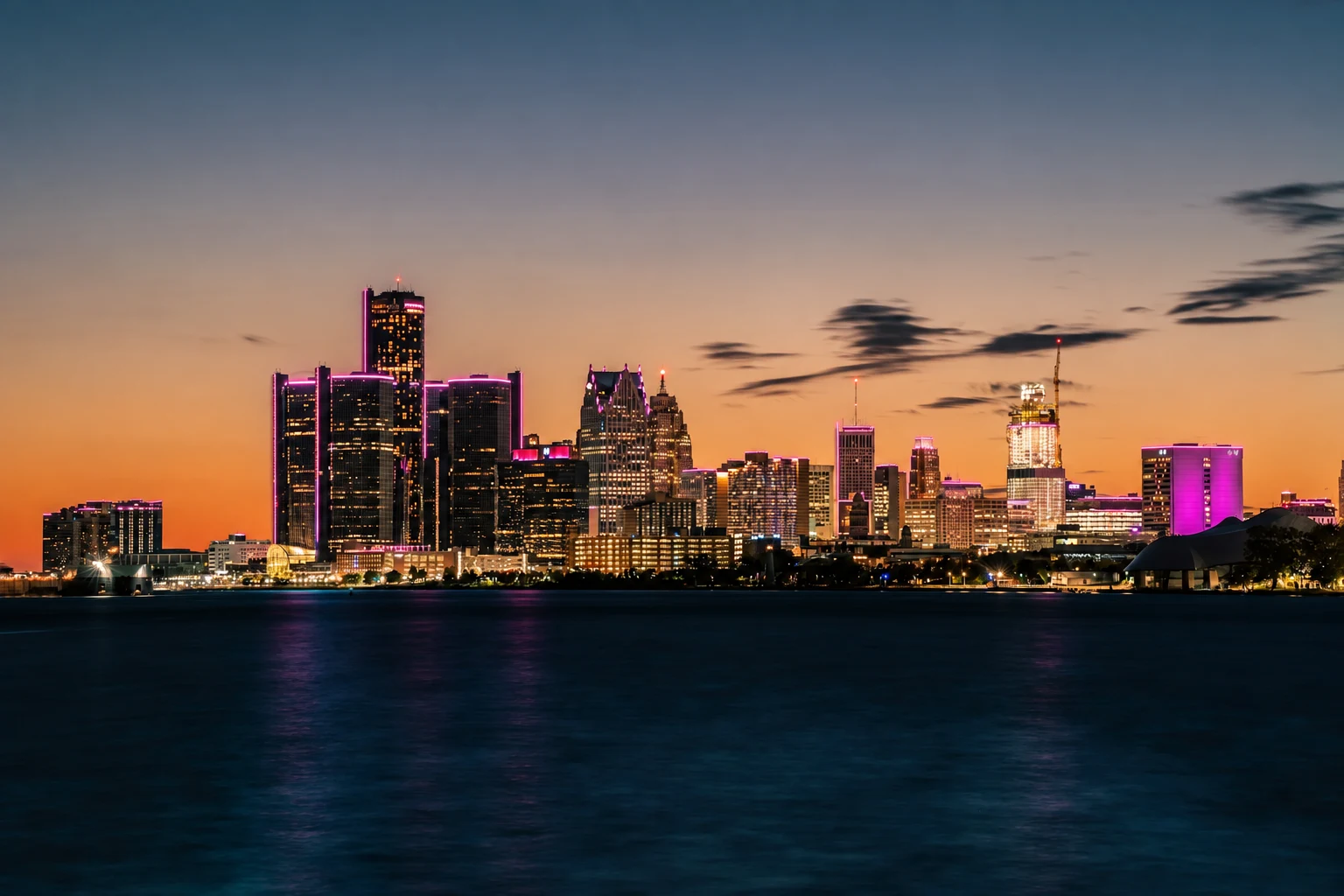 Detroit skyline at twilight with turquoise and purple building lights across the river