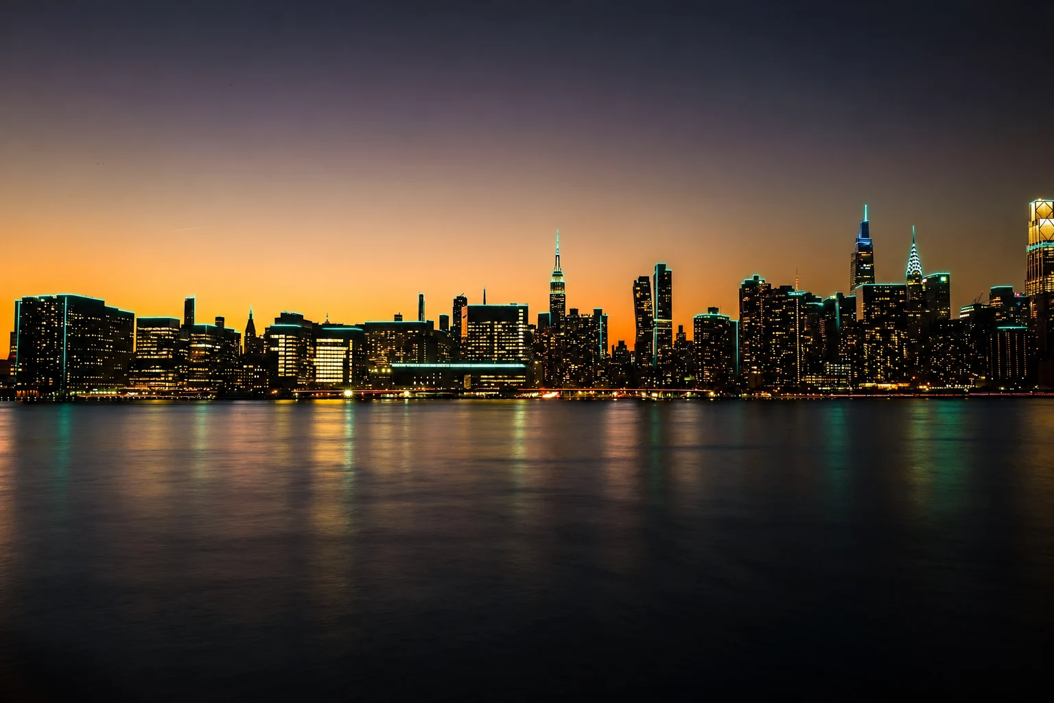Midtown Manhattan skyline and Empire State Building illuminated at sunset across the East River